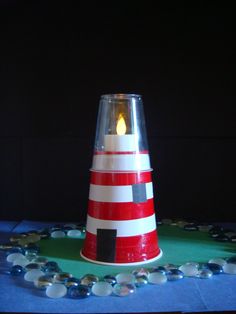 a red and white striped cone shaped candle holder on a blue table cloth with beads around it