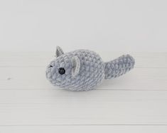 a small gray crocheted stuffed animal laying on top of a white wooden floor