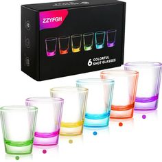 four different colored shot glasses sitting next to each other in front of a black box