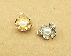 two charms sitting on top of a table next to each other, one with a pearl in the center