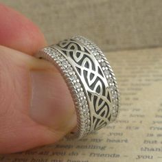 Sterling Silver Celtic Window to the Soul Ring with Enamel and CZs Continuous Sterling Silver Celtic Knot Design with white CZ Trim 10 mm Wide Grey Enamel Background Celtic Window to the Soul Design Collection Sizes whole and half 5 to 11 Boxed with a complementary silver cleaning cloth. Stamped .925 Ships in 3 to 5 days. (Sizes 5 or 6.5 in stock ships immediately.) Ships Free within the USA 21 Day Returns Items must be returned in new unworn condition. Engraved Diamond White Jewelry For Wedding, Engraved Cubic Zirconia Wedding Jewelry, Wedding Jewelry With Engraved Cubic Zirconia, Silver Rings With Pave Setting As A Gift, Silver Rings With Pave Setting For Gift, Silver Wedding Ring With Diamond Accents As Gift, Silver Wedding Jewelry With Diamond Accents As Gift, Silver Round Wedding Ring With Pavé Setting, Heirloom Silver Jewelry With Pave Setting