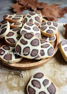 cookies decorated with chocolate and white frosting on a wooden platter surrounded by leaves