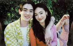 two young people are posing for a photo in front of some trees, one has her arm around the other's shoulder