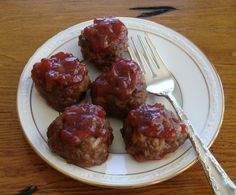 four meatballs on a plate with a fork