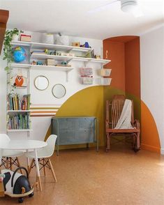 a room with two chairs, a table and some bookshelves on the wall