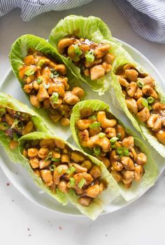 lettuce wraps filled with chicken and sauce on a white plate