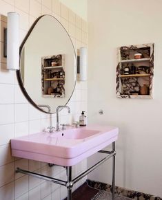 a pink sink sitting under a mirror in a bathroom