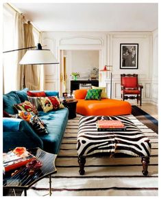 a living room filled with lots of furniture and colorful colors on the walls, along with a zebra print ottoman