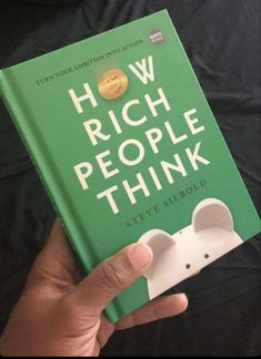 the book how rich people think is being held up in front of a black background