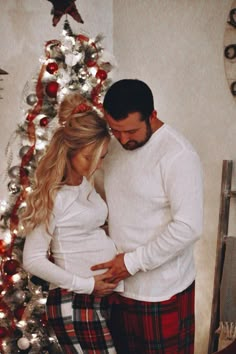 a man and woman standing in front of a christmas tree