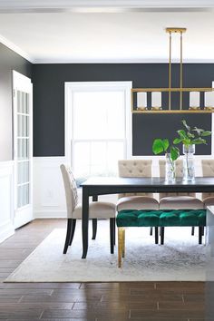 a dining room table with white chairs and a green bench in front of the window