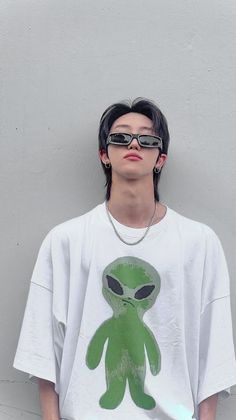 a young man with glasses and an alien t - shirt is standing in front of a wall