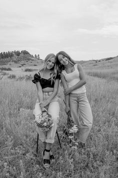 two beautiful young women standing next to each other in a field