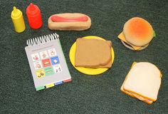 a table topped with sandwiches and condiments on top of a green carpeted floor