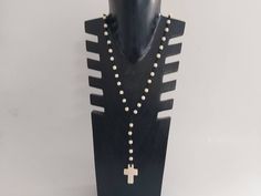 a black mannequin with white beads and a cross on it's neck