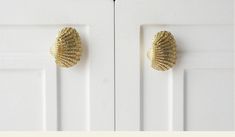 two white doors with gold knobs on the front and back sides, one has a shell shaped doorknob