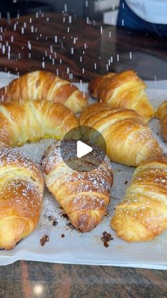 croissants and pastries sitting on top of a white tray with powdered sugar sprinkles