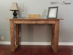 a wooden table sitting on top of a hard wood floor next to a white wall