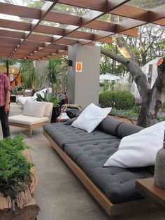 an outdoor living area with couches, tables and potted plants in the background