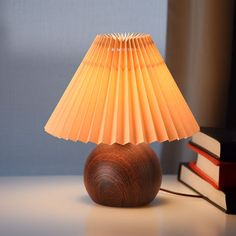 a table lamp sitting on top of a desk next to a stack of books and an open book