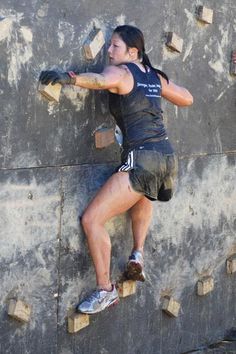 a woman climbing up the side of a rock wall