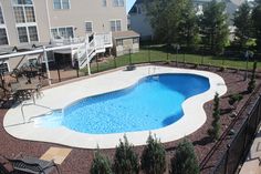 an above ground swimming pool surrounded by landscaping and fenced in area with patio furniture