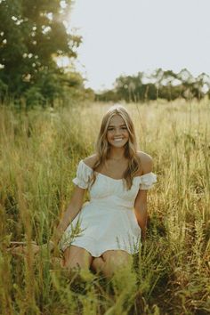 a woman sitting in tall grass smiling for the camera