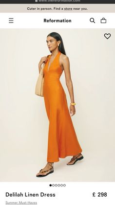 a woman is wearing an orange dress and holding a handbag in her right hand