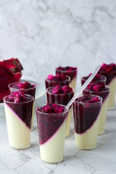 small cups filled with dessert sitting on top of a white table next to pomegranates