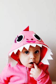 a small child wearing a pink shark costume