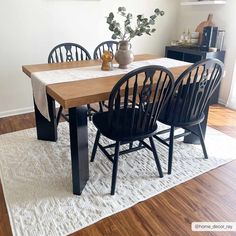 a dining room table with black chairs and a white rug