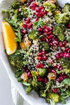 a white bowl filled with broccoli and pomegranate on top of a table