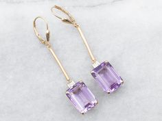 These elegant and luminous earrings feature yellow gold and amethyst set with a diamond accent, making it perfect for making a statement. Amethyst is known for its strength and protection properties, while the diamond accents provide the perfect touch of glam.Metal: 14K Yellow GoldGem: 2 Amethyst totaling 12.25 CaratsGem Measurements: 10.1 x 13.8 mm, Emerald CutAccents: 2 Diamonds totaling .10 Carats, SI in Clarity, G in ColorMeasurements: 10.1 x 54.3 mmMarks: "14KS" Stamped on the findings Amethyst Set, Glam Metal, Diamond Drops, Diamond Drop Earrings, Ruby Ring, Emerald Cut, Garnet, Jewelry Earrings Dangle, Dangle Drop Earrings