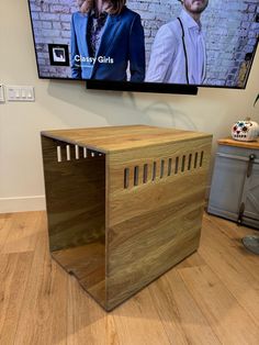 a tv mounted to the side of a wall next to a wooden box on top of a hard wood floor