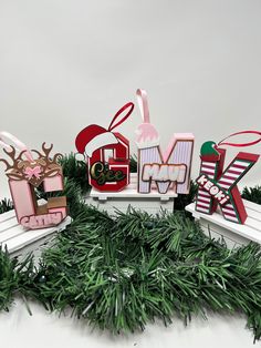 christmas decorations made out of wood and paper sit on top of a white bench with green grass