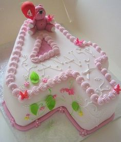 a birthday cake decorated with pink icing and teddy bear sitting on top of it