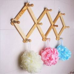 three wooden pegs are hanging on the wall with flower pom - poms