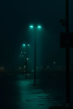 the street lights are lit up on a dark night in the parking lot with no cars