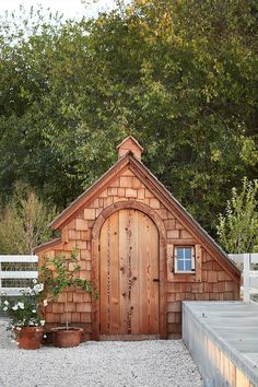 a small wooden building sitting next to a white fence