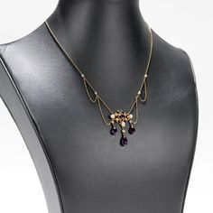 A fine Edwardian style festoon necklace.  In 14 karat yellow gold.  Centered on an ornate gold yolk with a bezel-set oval-cut amethyst.   Supporting 3 drops with freshwater river pearls and briolette-cut amethysts and flanked by several festooned swags punctuated by pearl mounts to the chain.  Simply a wonderful, delicate festoon necklace!  Date:  20th Century  Overall Condition: It is in overall good, as-pictured, used estate condition with some fine & light surface scratches and other signs of expected light wear consistent with age.  Fineness: Marked 14k for gold fineness.   Marks: Marked 14 to the clasp.  Gemstone Measurements: Amethyst cabochon: ca. 6.5 x 4.23 x  3.27 mm Largest Amethyst Drop: Length: ca. 9.5 mm Diam: ca. 5.2 mm  Measurements: Chain Length: ca. 16 in. Pendant: Height: Yellow Gold Amethyst Necklace For Wedding, Formal Purple 14k Gold Necklace, Formal Yellow Gold Amethyst Necklace, Fine Jewelry Amethyst Necklaces In Yellow Gold, Fine Jewelry Amethyst Necklace In Yellow Gold, Fine Jewelry Yellow Gold Amethyst Necklaces, Purple Heirloom Pendant Necklace, Elegant Purple Oval Pendant Necklace, Heirloom Purple Pendant Necklace