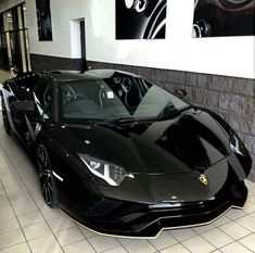 a black sports car parked in a showroom with white tile flooring and walls