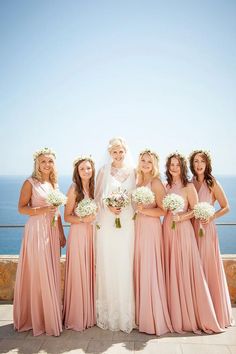 the bride and her bridesmaids pose for a photo in front of the ocean