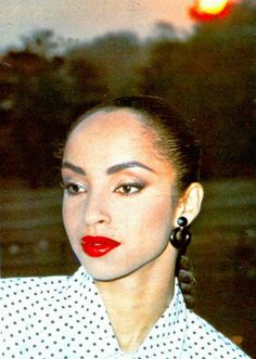 a woman with red lipstick and black earrings standing in front of a street light at night