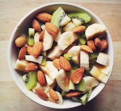 a white bowl filled with sliced fruit and nuts