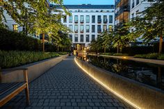 a bench sitting on the side of a brick road next to trees and buildings at night