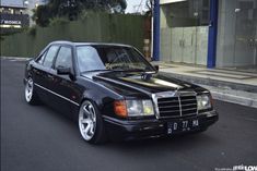 a black mercedes benz parked on the side of the road in front of a building