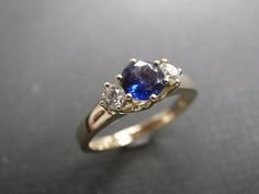 This brilliant three-stone engagement ring is set in 14K White / yellow gold. The center stone, a 5mm round brilliant cut natural blue sapphire is set in a four prong setting and adorned by two round brilliant cut diamonds with total carat weight of 0.20cttw. Diamonds Quality: D-F in Color and VS in Clarity with Heart and Arrow (Ideal cut) Currently made to order pieces may take up to 10-15 business days to complete, or let me know if you need it urgent. You may also like: A similar diamond and Classic Blue Wedding Ring With Diamond Accents, Timeless Blue Wedding Dress, Sapphire Three Stone Wedding Diamond Ring, Blue Diamond Three Stone Wedding Ring, Blue Three Stone Diamond Wedding Rings, White Gold Three Stone Sapphire Wedding Ring, Wedding Sapphire Three Stone Ring, Formal Three Stone Sapphire Wedding Ring, Formal Sapphire Three Stone Wedding Ring