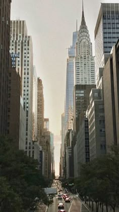 a city street lined with tall buildings and cars driving down it's side in the distance