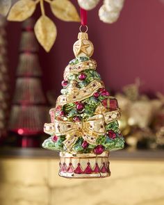 a christmas tree ornament hanging from a red and gold ribbon on a table