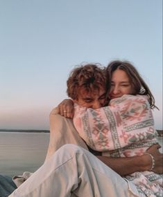 two people hugging each other on the beach